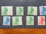 plusieurs timbres de différentes couleurs posés sur un papier noir, posé à son tour sur une table en bois