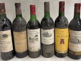 six bouteilles de vin sont alignées sur une surface blanche