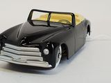 a black toy car with a yellow top on a white surface