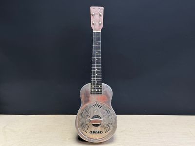 une petite guitare en métal posée sur une table en bois