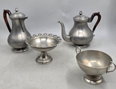 trois théières en argent et un bol posés sur une table