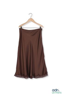 dark brown skirt hanging on a hanger against a white wall