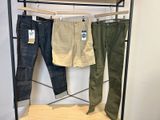 trois pantalons pour homme suspendus à un portant dans un magasin de vêtements