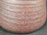 a close up of a brown vase on a black surface