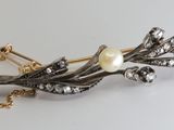 a silver and gold brooch with pearls on it