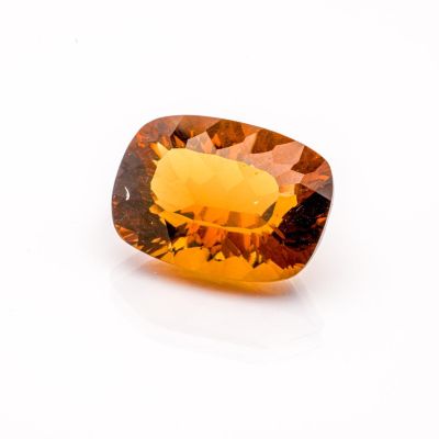 a close up of a yellow sapphire stone on a white surface
