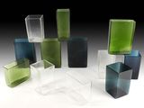 de nombreux vases en verre de différentes couleurs posés sur une surface blanche