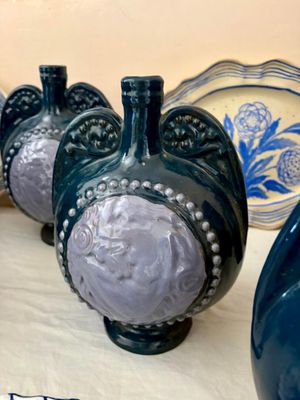 Plusieurs vases bleus sont alignés sur une table recouverte d'une nappe blanche.