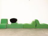 a green couch and a black chair in a white room