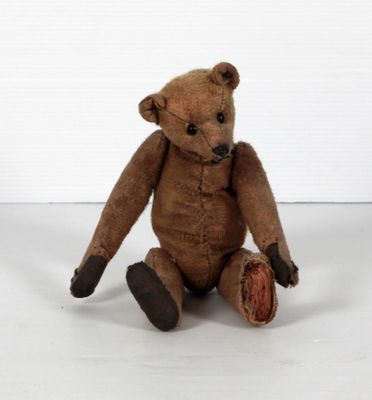 un ours en peluche marron assis par terre