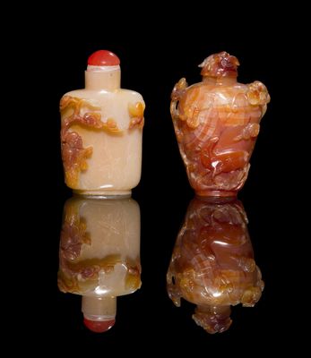 pair of chinese carved glass snuff bottles on a reflective surface