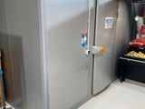 a silver refrigerator in the middle of a room next to a pile of food