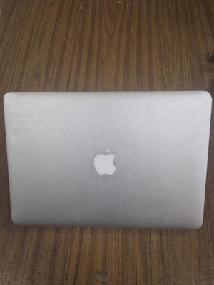 un ordinateur portable Apple posé sur une table au plateau en bois