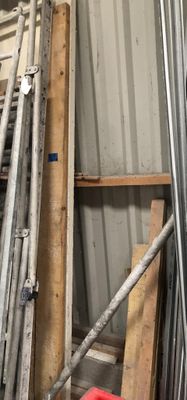 a pile of metal pipes in a room with a red bucket