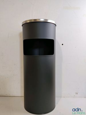 une image représentant une poubelle noire posée sur un mur blanc