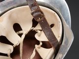 a helmet with a leather strap hanging from it ' s side