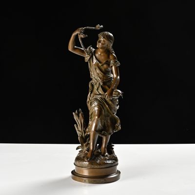 une statue en bronze d'une femme tenant un oiseau sur un piédestal