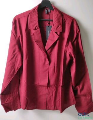 une veste rouge suspendue à un cintre devant un mur blanc