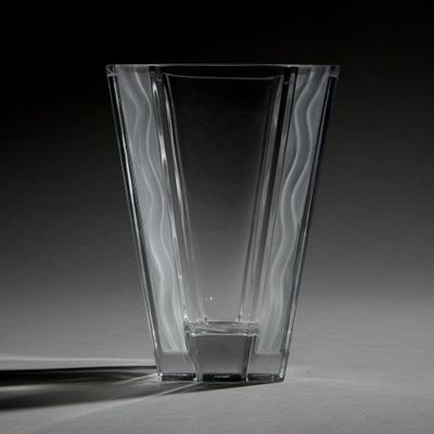 un vase en verre posé sur une table, dont l'ombre se projette sur le sol