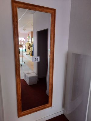 un miroir dans un coin d'une pièce, sur lequel est accrochée une pancarte