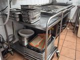 several pans and pans are stacked on a metal cart in a kitchen