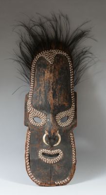 une image représentant un masque en bois orné de plumes sur fond blanc