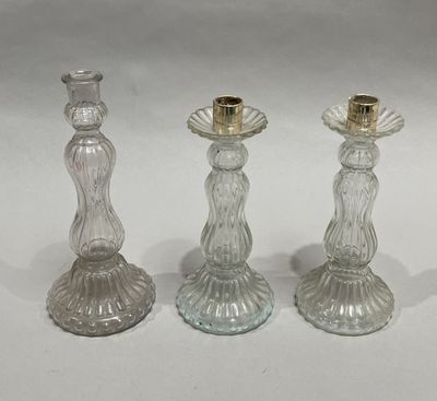 three clear glass candlesticks with gold rims on a white surface