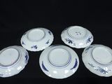 four blue and white plates with designs on them on a black surface