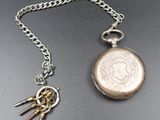 a silver pocket watch with a chain and a key