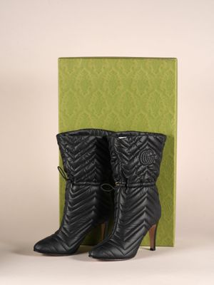 une paire de bottes noires posée sur une boîte verte