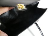 a person holding a black purse with a gold clasp