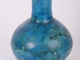 un vase bleu posé sur une surface blanche