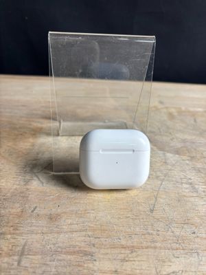 des AirPods de la marque Apple posés sur une table en bois, à côté d'une boîte transparente