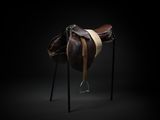 the saddle of a horse on a stand against a black background