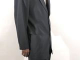 a man in a suit and tie standing in front of a white wall
