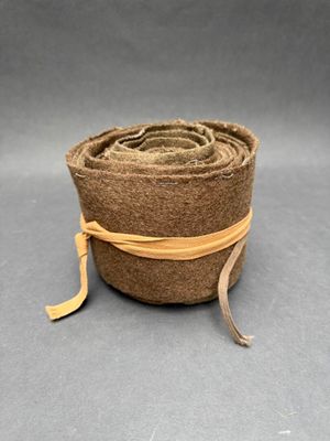 rouleau de laine marron enroulé, orné d'un ruban jaune, sur fond gris
