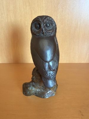 statue d'un hibou perché sur une branche, posée sur une table en bois