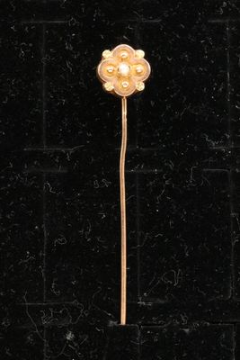 un gros plan d'une broche en forme de fleur dorée sur fond noir