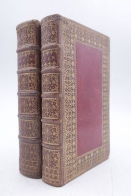 two old books that are sitting on a white surface