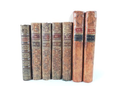 several old books are lined up in a row on a white surface
