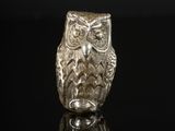 une figurine de chouette en argent posée sur une surface noire