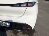 the rear end of a white car parked in a parking lot
