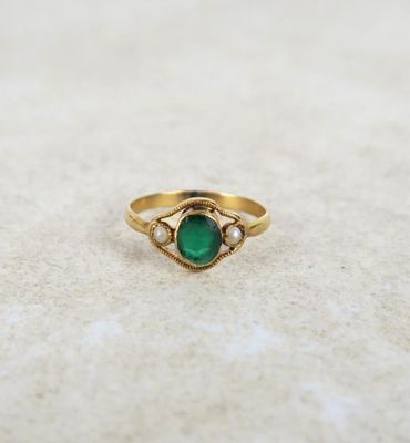 a close up of a gold ring with a green stone