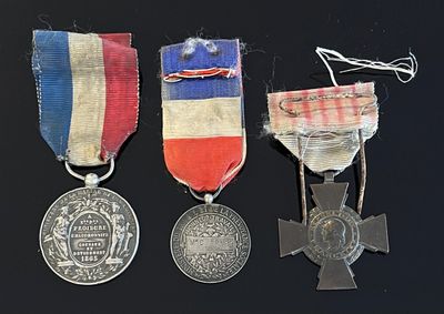 trois médailles et une croix sont disposées sur un fond noir