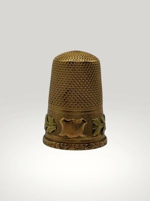 a gold thimble with a design on it