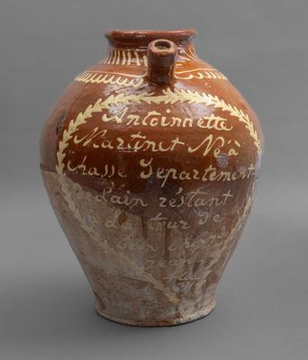 un vase marron portant une inscription, posé sur une table