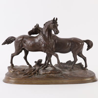 bronze sculpture of two horses on a rock with a white background