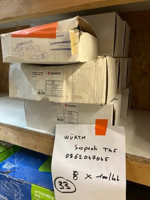 une pile de cartons posée sur une étagère, sur laquelle est accrochée une pancarte