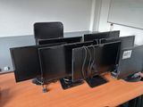 four computer monitors sitting on a desk in an office