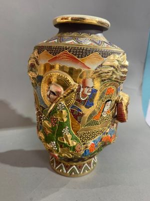 un vase en or orné d'une image représentant des personnes